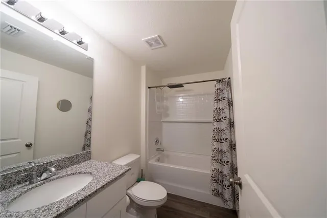 a bathroom with a granite countertop sink toilet and shower