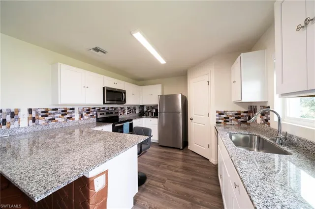 a kitchen with stainless steel appliances granite countertop a refrigerator a stove and a sink