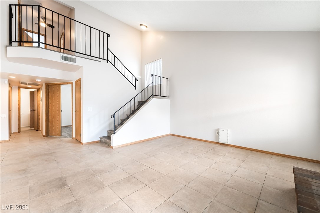 516 Inness Avenue Henderson, NV 89011 - Photo 14 of 42 Unfurnished living room featuring high vaulted ceiling, stairs, and light tile patterned floors