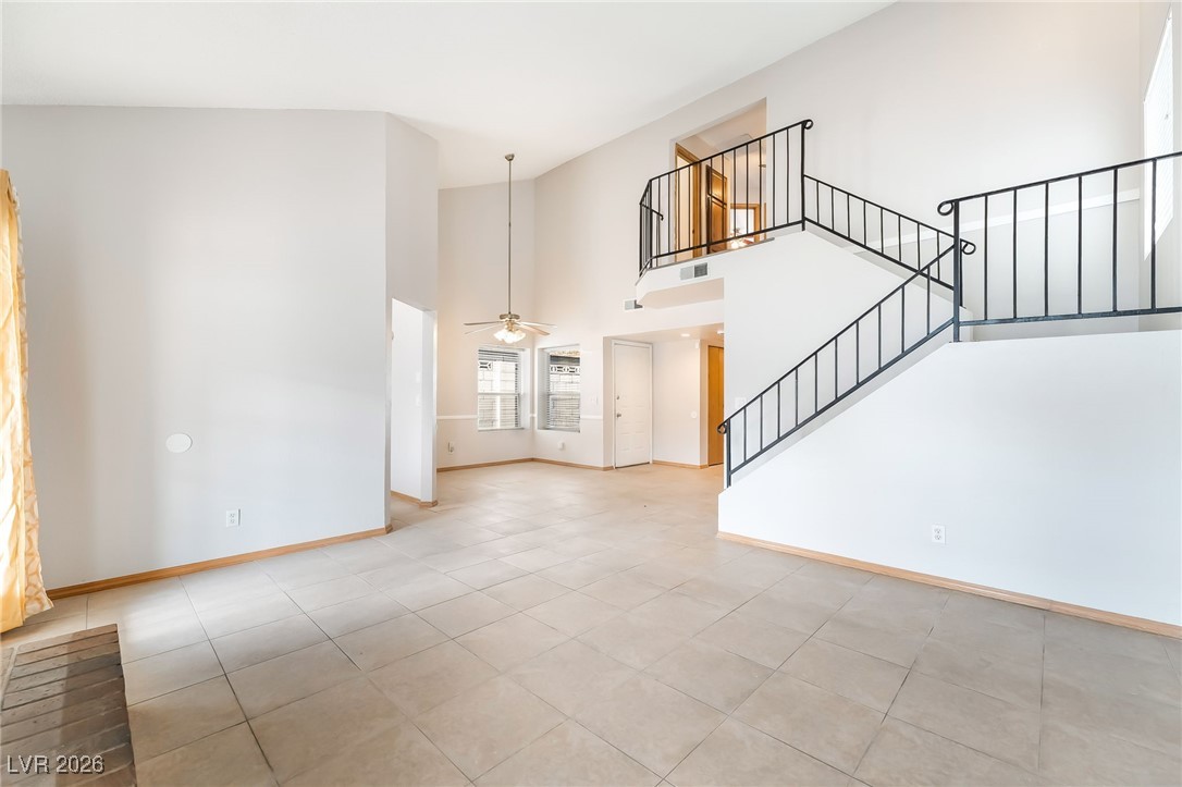 516 Inness Avenue Henderson, NV 89011 - Photo 15 of 42 Unfurnished living room with a towering ceiling, a ceiling fan, stairway, and light tile patterned floors