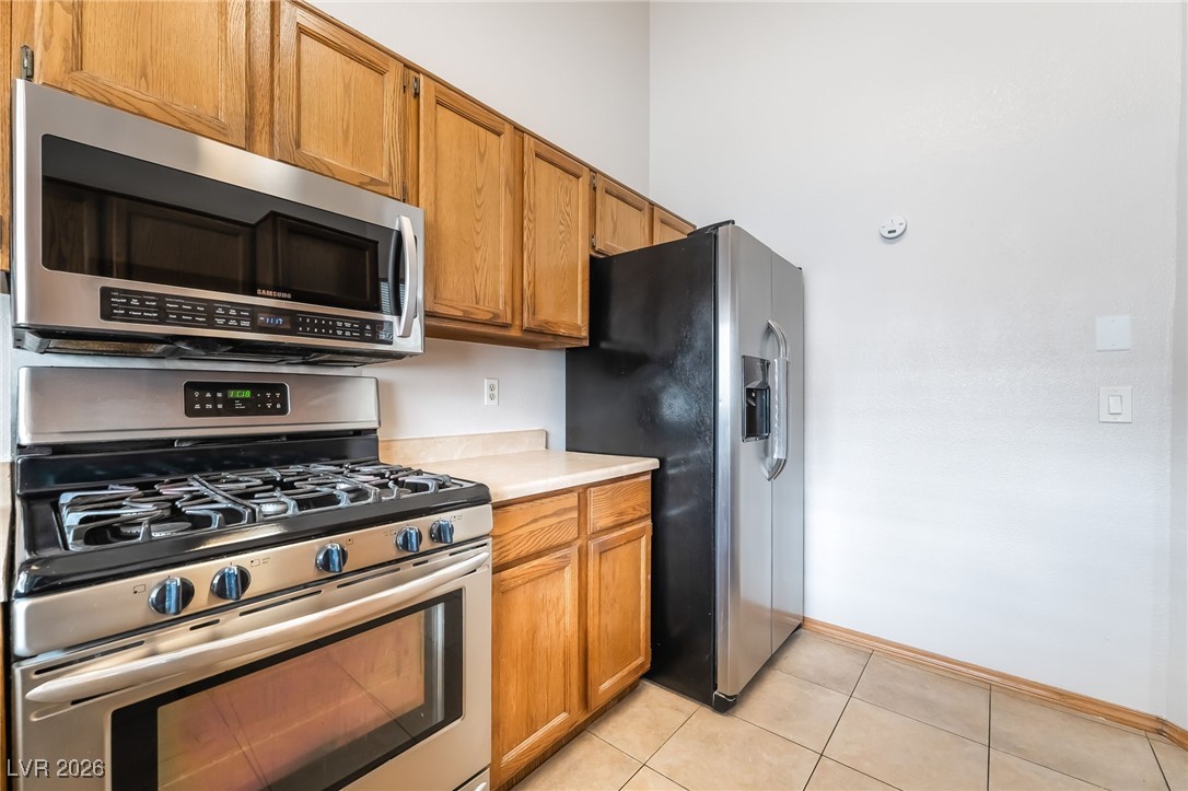 516 Inness Avenue Henderson, NV 89011 - Photo 18 of 42 Kitchen with appliances with stainless steel finishes, light countertops, brown cabinets, and light tile patterned flooring