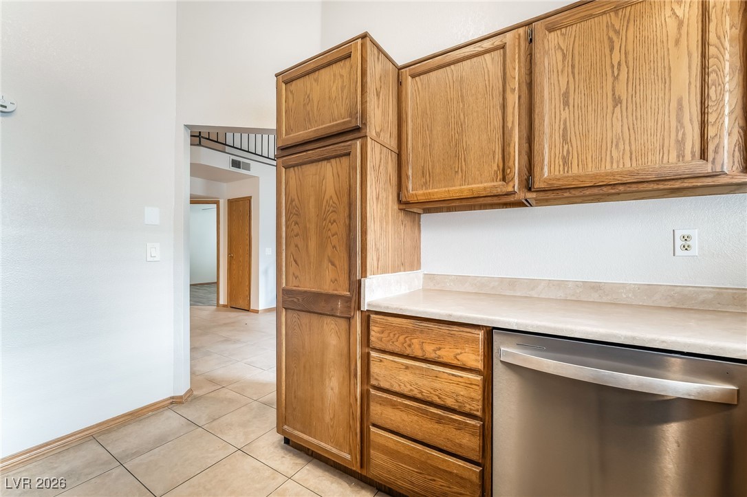 516 Inness Avenue Henderson, NV 89011 - Photo 19 of 42 Kitchen with stainless steel dishwasher, light countertops, light tile patterned floors, and brown cabinets