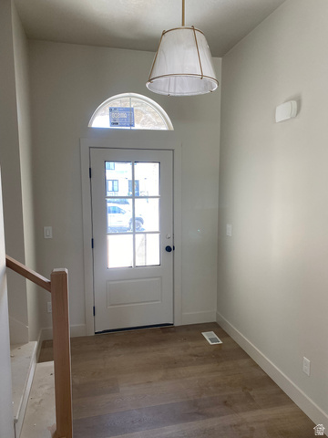 4676 West 75 North, Unit 401 West Point, UT 84015 - Photo 19 of 25 Entryway featuring a glass-paneled door with an arched transom window, wood-finish flooring, and a contemporary pendant light fixture