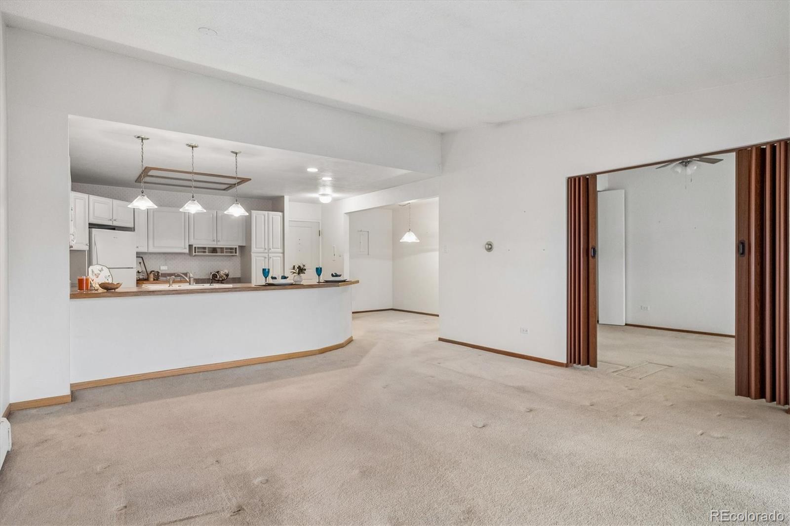 650 South Clinton Street, Unit 5D Denver, CO 80247 - Photo 9 of 48 a view of a kitchen with refrigerator and white cabinets