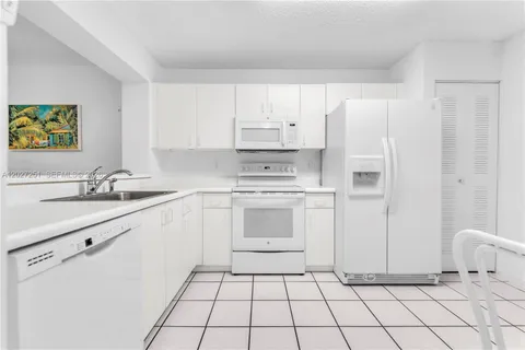 a kitchen with white cabinets appliances and a sink