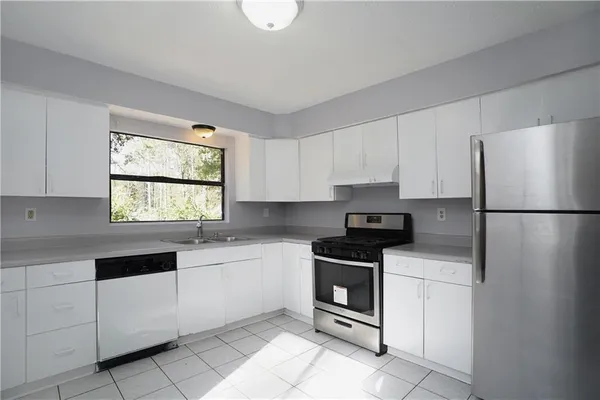 a kitchen with granite countertop white cabinets white stainless steel appliances and sink