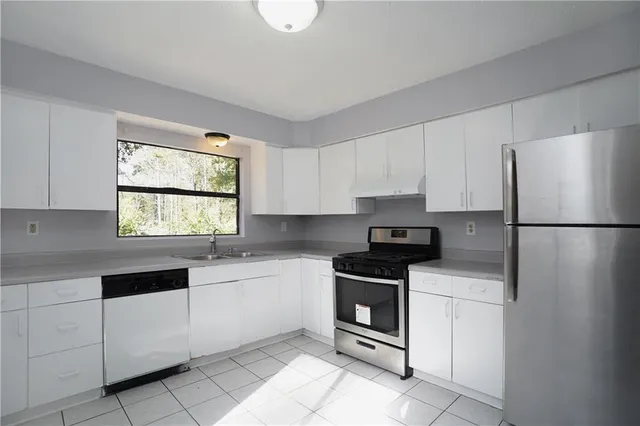a kitchen with granite countertop white cabinets white stainless steel appliances and sink