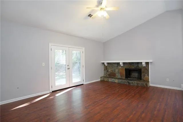an empty room with wooden floor fire place and windows