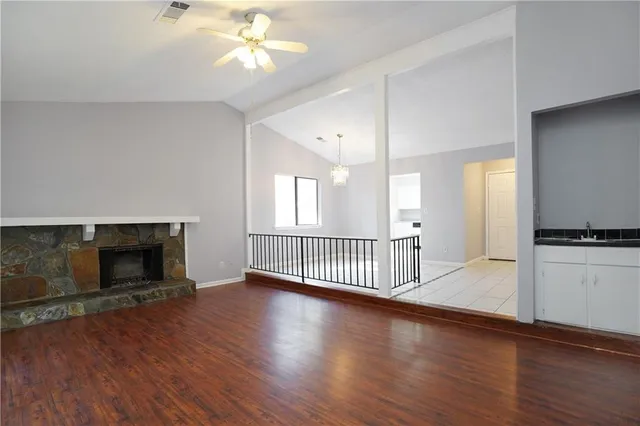 an empty room with wooden floor a fireplace and windows
