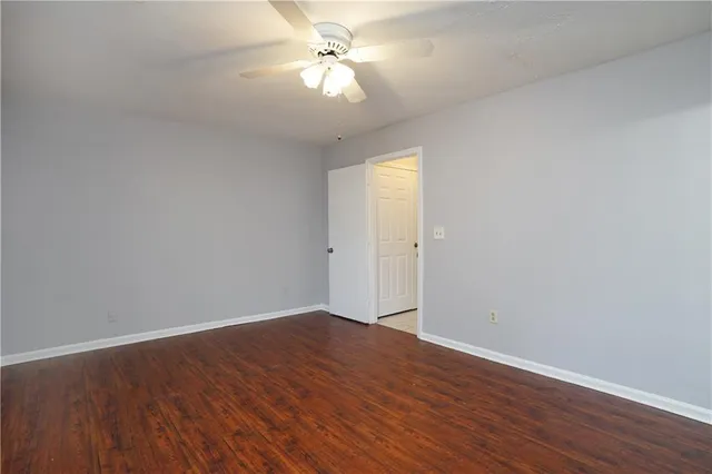 an empty room with wooden floor and fan