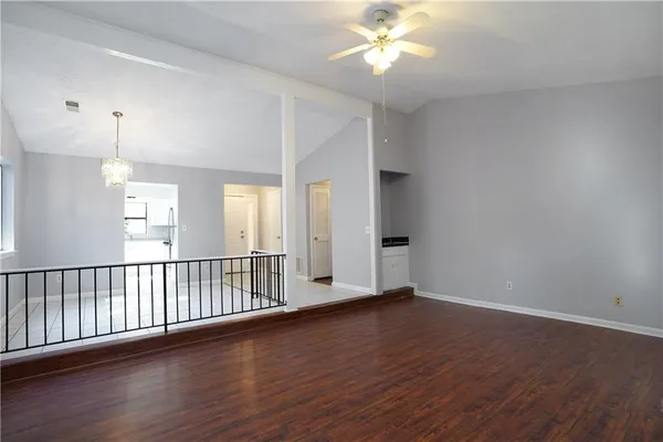 an empty room with wooden floor fan and windows