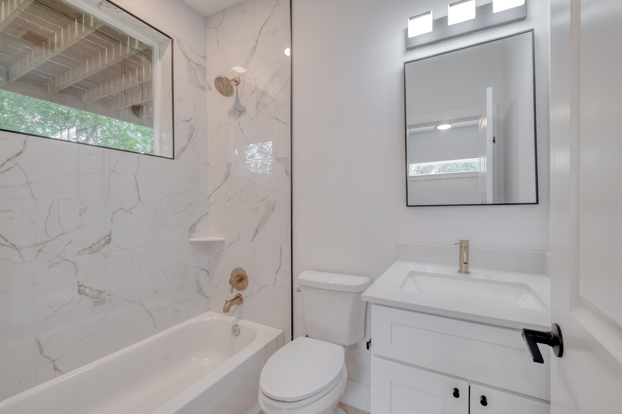 5211 Rob-Scott Street Austin, TX 78721 - Photo 20 of 24 A well-lit bathroom features a shower-tub combination with elegant tile and a modern vanity.