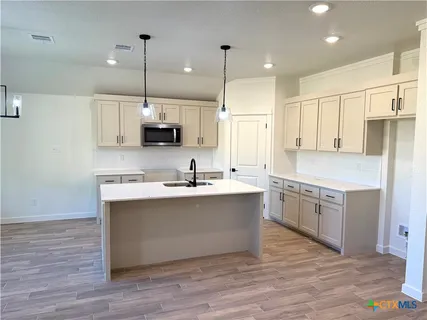 a large kitchen with stainless steel appliances sink a stove and wooden floor