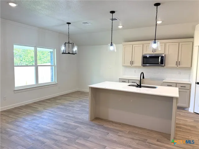 a kitchen with kitchen island a sink and a wooden floor
