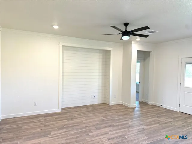 an empty room with wooden floor a ceiling fan and closet