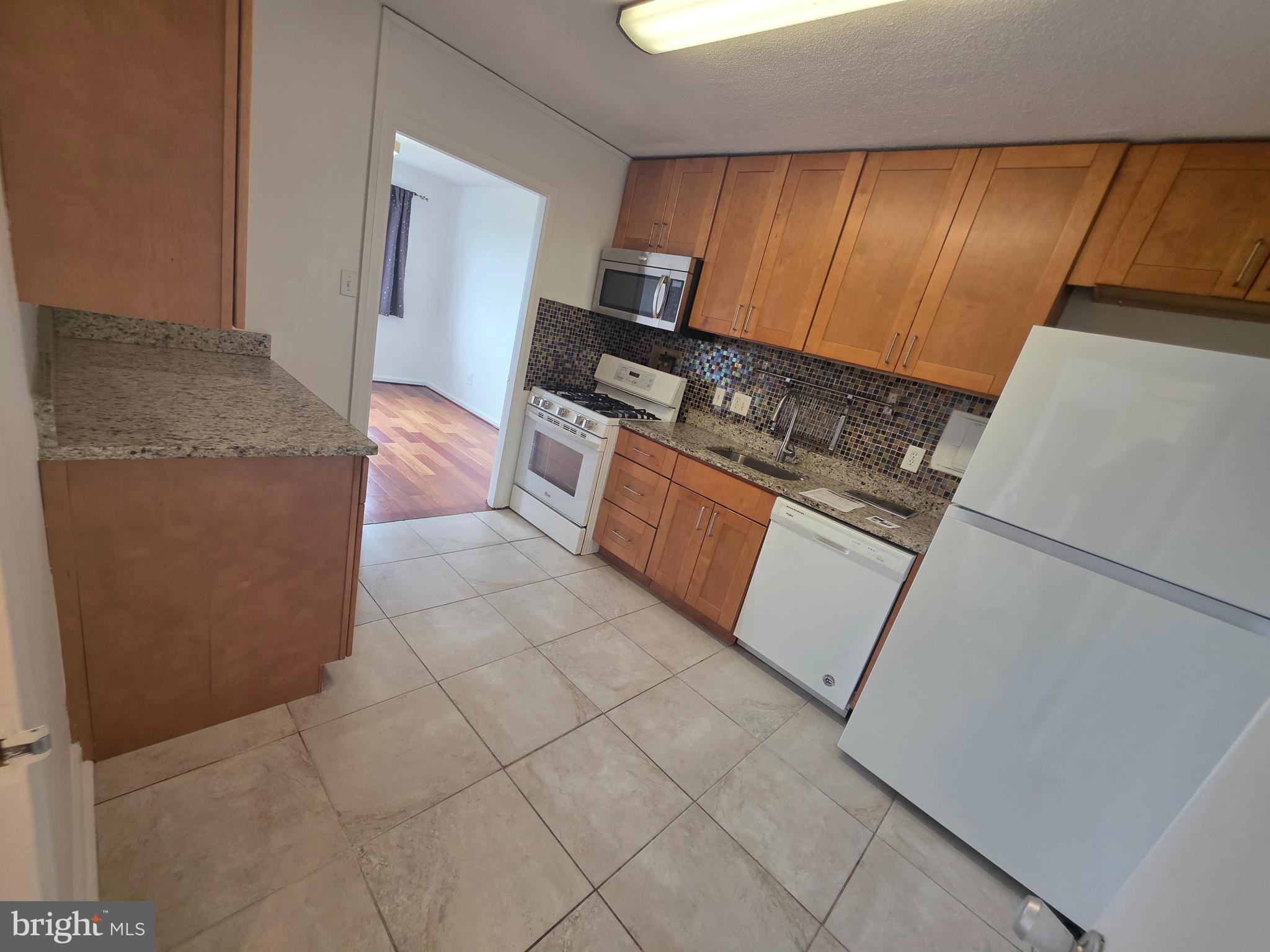1836 Metzerott Road, Unit 1704 Adelphi, MD 20783 - Photo 26 of 47 a kitchen with granite countertop a refrigerator stove and cabinets