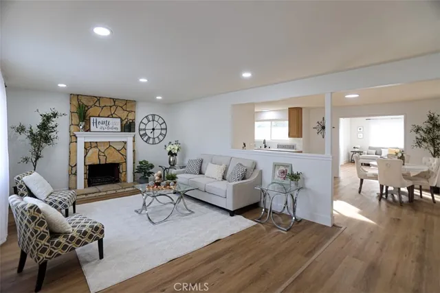 a living room with furniture a fireplace and a dining table with wooden floor