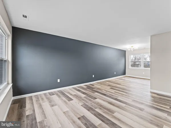 a view of an empty room with a window and wooden floor
