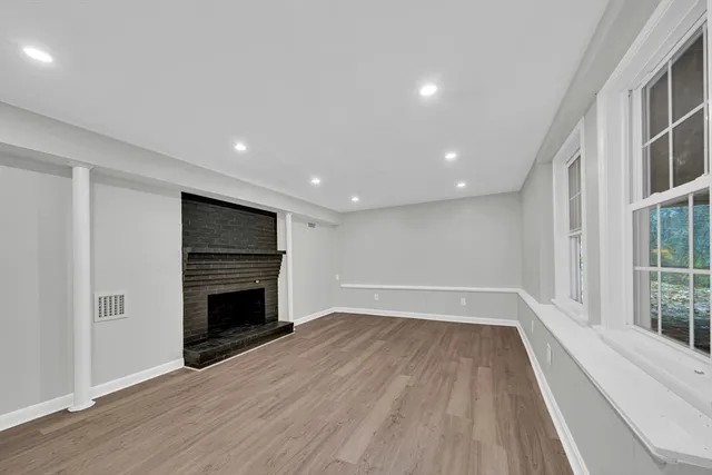 a view of empty room with wooden floor and fireplace