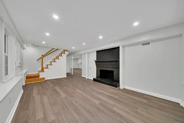 an empty room with wooden floor fireplace and staircase