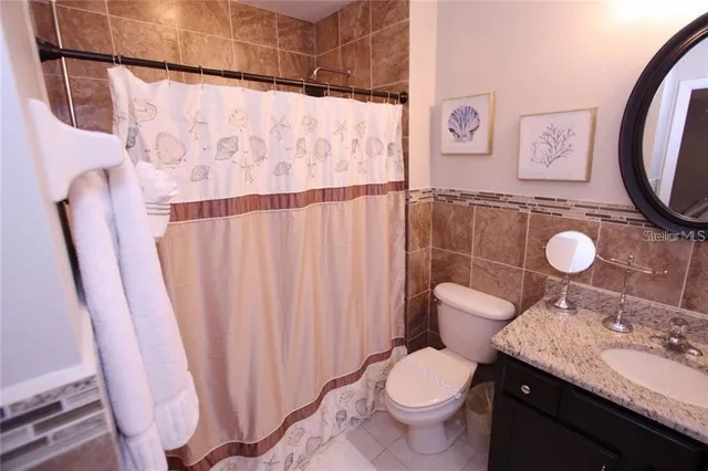 a bathroom with a granite countertop toilet and a sink
