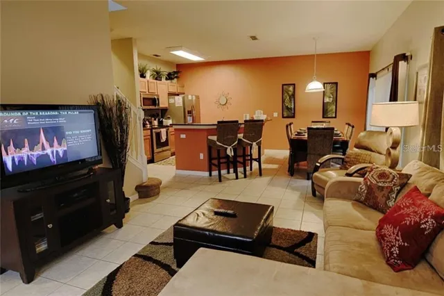 a living room with furniture a flat screen tv and kitchen view