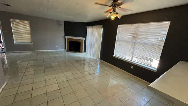 an empty room with windows and fireplace