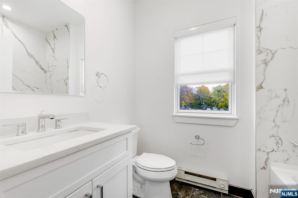 74 Clarendon Place, Unit 202 Hackensack, NJ 07601 - Photo 23 of 32 a bathroom with a sink toilet and a mirror