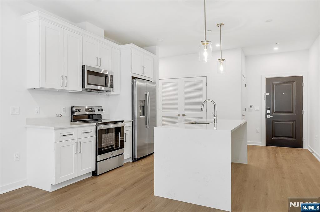 74 Clarendon Place, Unit 202 Hackensack, NJ 07601 - Photo 4 of 32 a kitchen with white cabinets and stainless steel appliances