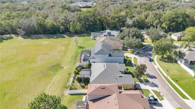 an aerial view of residential house with swimming pool and large trees