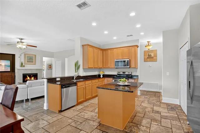 a kitchen with granite countertop a stove top oven a sink dishwasher and a refrigerator with wooden floor