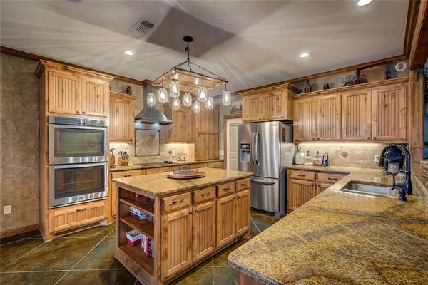 a kitchen with stainless steel appliances granite countertop a stove refrigerator and cabinets