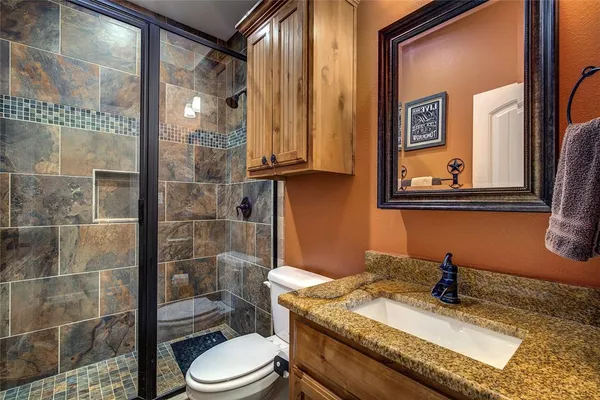 a bathroom with a granite countertop sink a toilet and shower