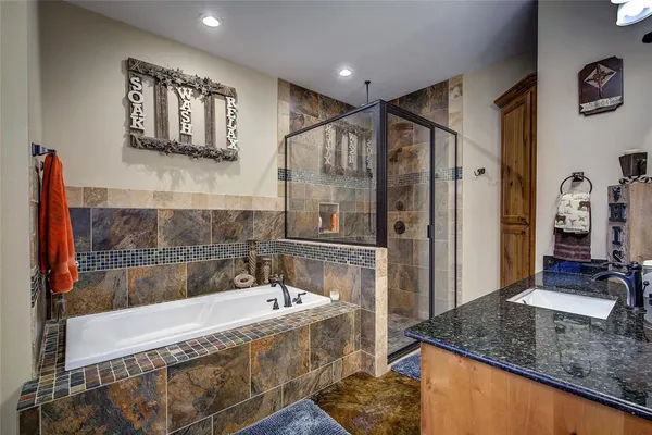 a bathroom with a granite countertop tub sink and mirror
