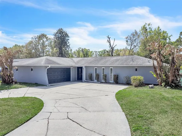 a front view of house with yard and trees in the background