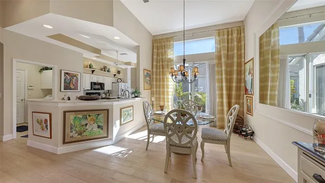 a kitchen with stainless steel appliances kitchen island granite countertop a refrigerator a sink dishwasher a dining table and chairs with wooden floor