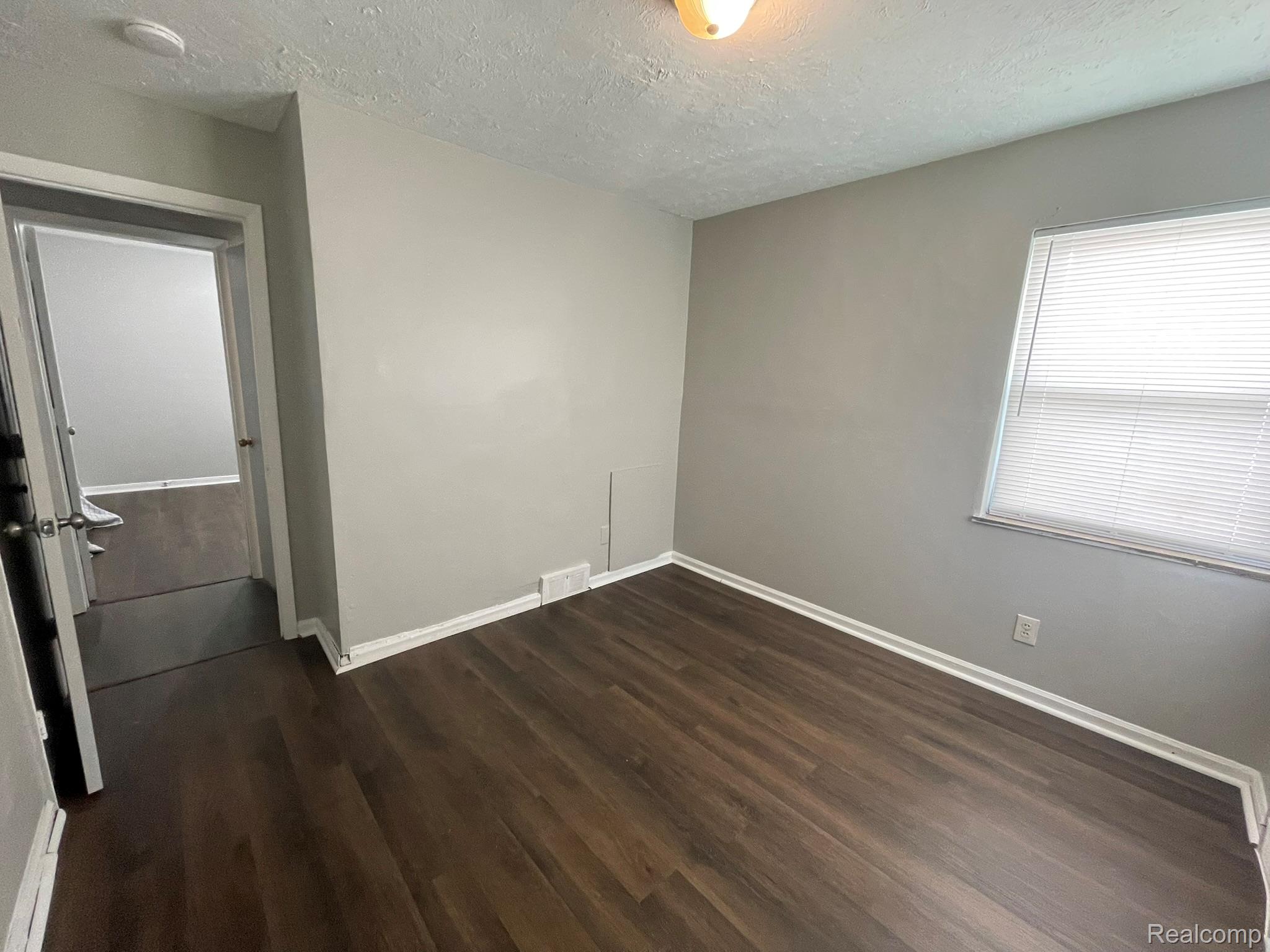 19800 Berg Road Detroit, MI 48219 - Photo 11 of 13 Room featuring wood-finish flooring, light gray wall paint, and white trim