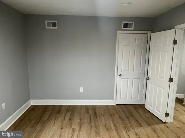 a view of an empty room with wooden floor and closet area