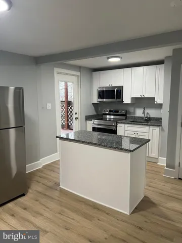 a kitchen with granite countertop a refrigerator and a stove top oven