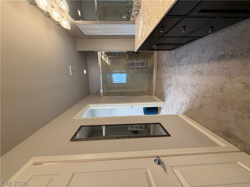 6385 Jackson Spring Road Las Vegas, NV 89118 - Photo 25 of 36 Luxurious primary bath featuring a dual vanity, sleek dark cabinetry, and a spacious glass-enclosed shower.