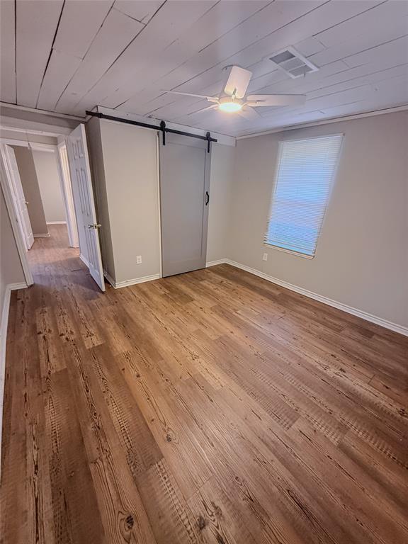 117 East Division Street Pilot Point, TX 76258 - Photo 7 of 19 Bedroom1 - Wood-finish flooring throughout, complemented by a white planked ceiling with a ceiling fan