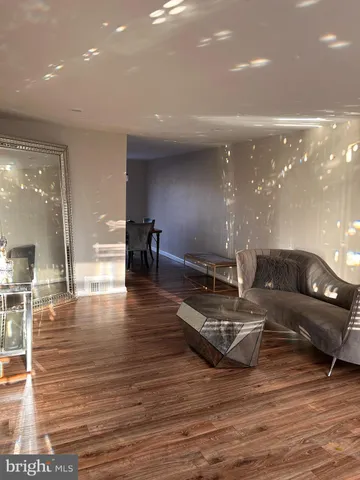 a living room with couches and kitchen view with wooden floor