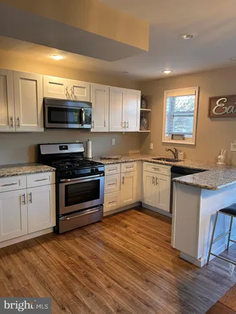 a kitchen with granite countertop a sink cabinets and stainless steel appliances