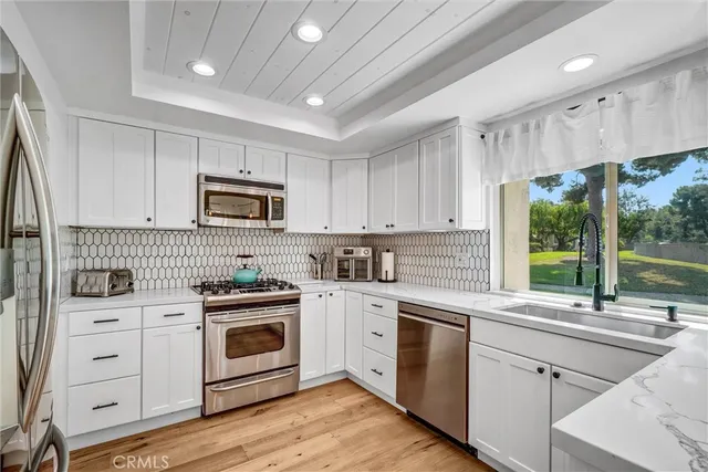 a kitchen with cabinets stainless steel appliances a sink and a window