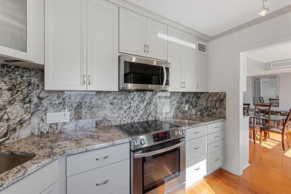 136 Lakeshore Drive, Unit PH10 North Palm Beach, FL 33408 - Photo 5 of 38 a kitchen with granite countertop white cabinets and black stainless steel appliances