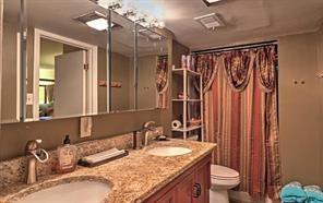 843 Artwood Road Northeast, Unit 843 Atlanta, GA 30307 - Photo 2 of 18 a bathroom with a granite countertop sink a toilet a mirror and shower curtain