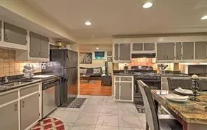 a kitchen with stainless steel appliances granite countertop a stove top oven a sink a dining table and chairs with wooden floor