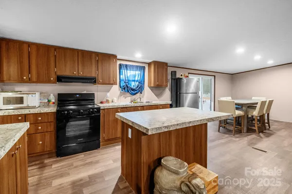 a kitchen with stainless steel appliances granite countertop a stove top oven a sink dishwasher and a refrigerator with wooden cabinets