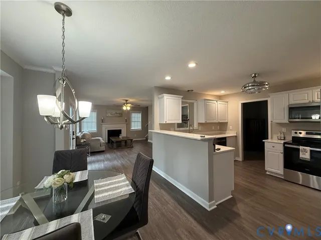 a kitchen with stainless steel appliances kitchen island granite countertop a table chairs refrigerator and microwave