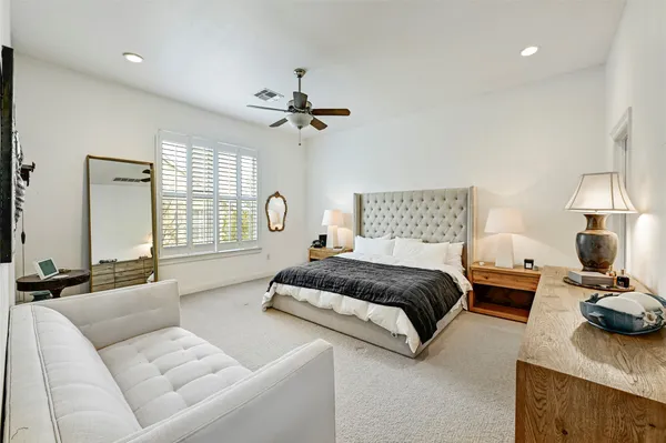 a spacious bedroom with a bed a couch and a chandelier